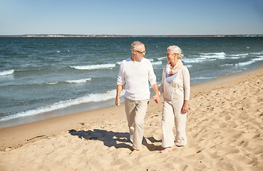 Image showing happy senior couple walking along summer beach