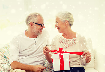 Image showing happy senior couple with gift box at home