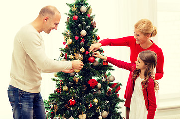 Image showing smiling family decorating christmas tree at home