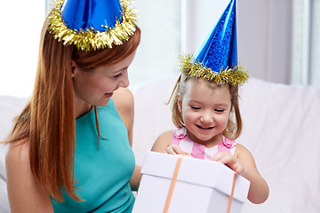 Image showing happy mother and child in party caps with gift box