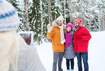 Image showing smiling friends with tablet pc in winter forest