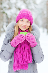 Image showing smiling young woman with cup in winter forest