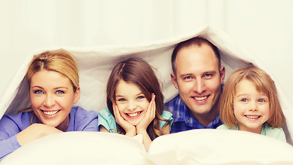 Image showing happy family with two kids under blanket at home