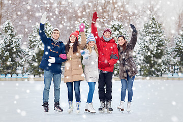 Image showing happy friends ice skating on rink outdoors