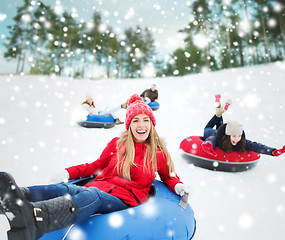 Image showing group of happy friends sliding down on snow tubes