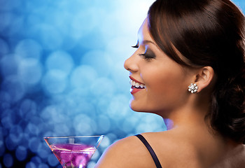 Image showing smiling woman holding cocktail over blue lights