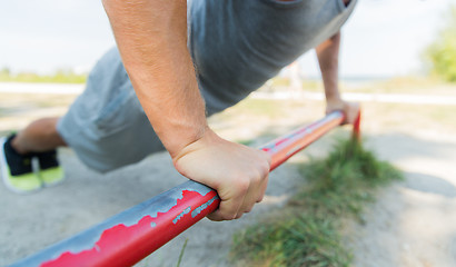 Image showing young man exercising on horizontal bar outdoors