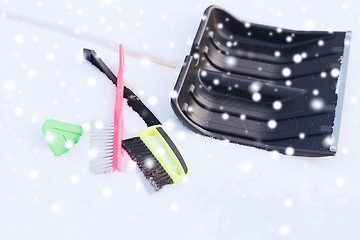 Image showing black snowshowel with wooden handle in snow pile