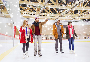 Image showing happy friends pointing finger on skating rink