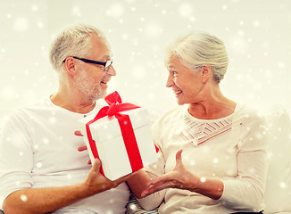 Image showing happy senior couple with gift box at home