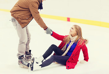 Image showing man helping women to rise up on skating rink