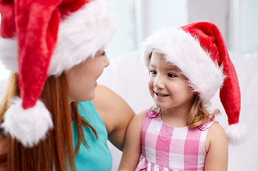 Image showing happy mother and little girl in santa hats at home