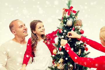 Image showing smiling family decorating christmas tree at home