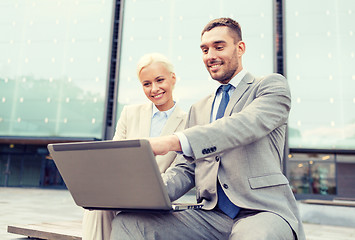 Image showing smiling businesspeople with laptop outdoors