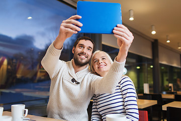 Image showing happy couple with tablet pc taking selfie at cafe