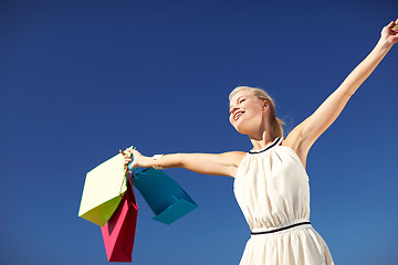 Image showing smiling woman with shopping bag rising hands