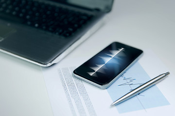 Image showing close up of smartphone, laptop and pen on table