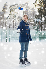 Image showing happy young man with smartphone on ice rink