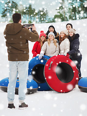 Image showing group of smiling friends with snow tubes