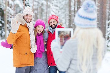 Image showing smiling friends with tablet pc in winter forest