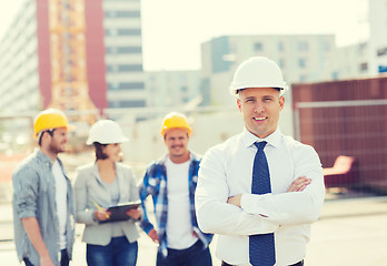 Image showing group of smiling builders in hardhats outdoors