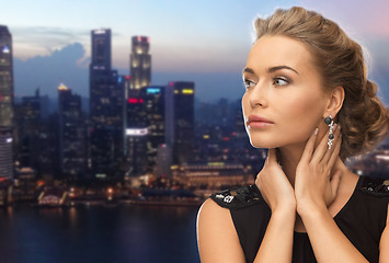 Image showing beautiful woman wearing earrings over evening city