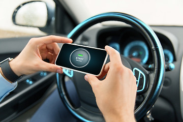 Image showing hands with start engine icon on smartphone in car