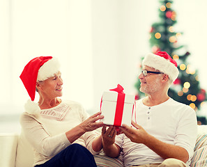 Image showing happy senior couple in santa hats with gift box