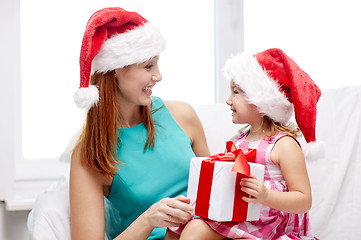 Image showing happy mother and child in santa hats with gift box