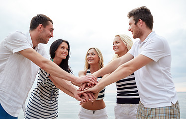 Image showing smiling friends putting hands on top of each other