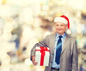 Image showing smiling man in suit and santa helper hat with gift