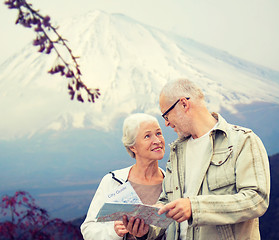 Image showing happy senior couple with travel map over mountains