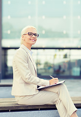 Image showing young smiling businesswoman with notepad outdoors