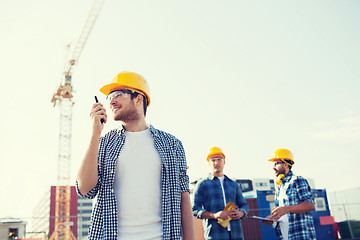 Image showing group of smiling builders in hardhats with radio