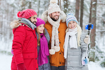 Image showing smiling friends with smartphone in winter forest