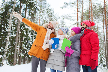 Image showing smiling friends with tablet pc in winter forest