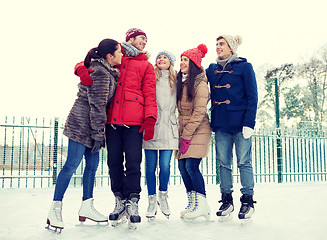 Image showing happy friends ice skating on rink outdoors