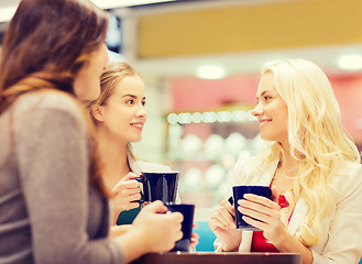 Image showing smiling young women with cups in mall or cafe