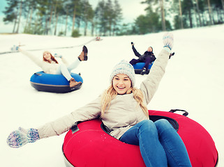 Image showing group of happy friends sliding down on snow tubes