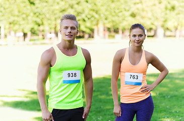 Image showing happy friends or couple with racing badge numbers