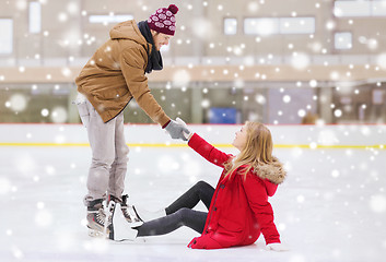 Image showing man helping women to rise up on skating rink