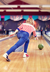 Image showing happy young woman throwing ball in bowling club