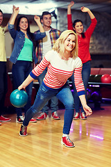 Image showing happy young woman throwing ball in bowling club