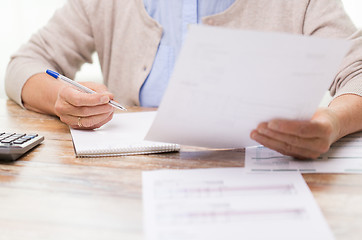 Image showing senior woman with papers and calculator at home