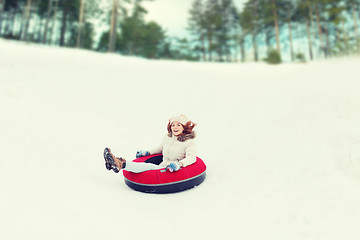 Image showing happy teenage girl sliding down on snow tube