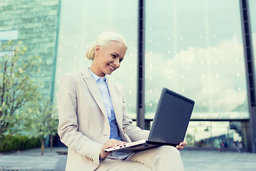 Image showing smiling businesswoman working with laptop outdoors