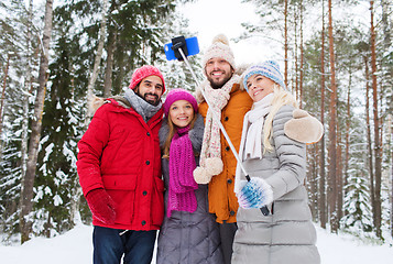 Image showing smiling friends with smartphone in winter forest