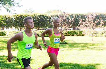 Image showing happy sportsmen couple racing wit badge numbers