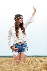 Image showing smiling hippie woman on cereal field waving hand