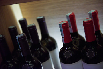 Image showing Wine bottles on a wooden shelf.